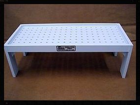 A white table with holes in it is sitting on a brown surface.
