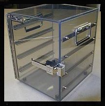 A clear acrylic box with handles is sitting on a table.