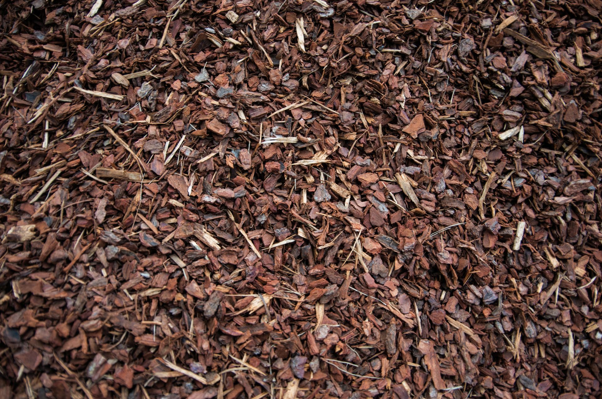 A pile of brown mulch is sitting on the ground.