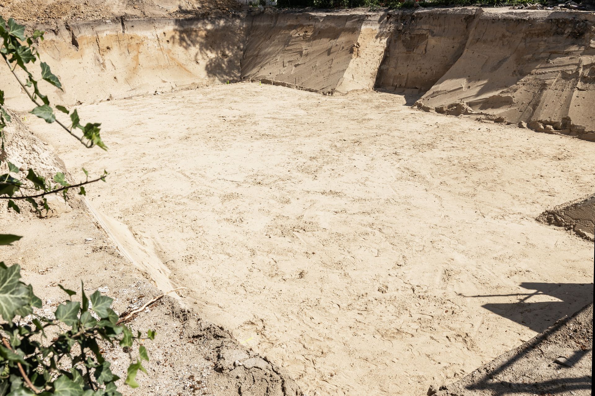 A large pile of sand is sitting in the middle of a dirt field.
