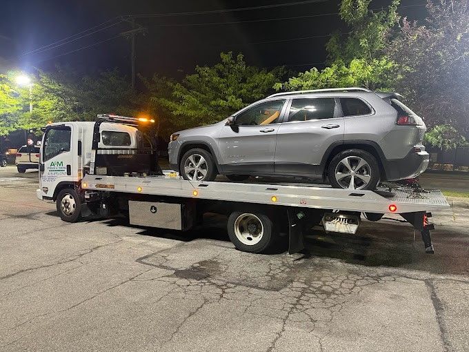 A car is being towed by a tow truck at night.