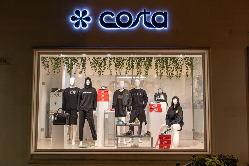 Vetrina del negozio Costa con manichini in abbigliamento sportivo e accessori neri.