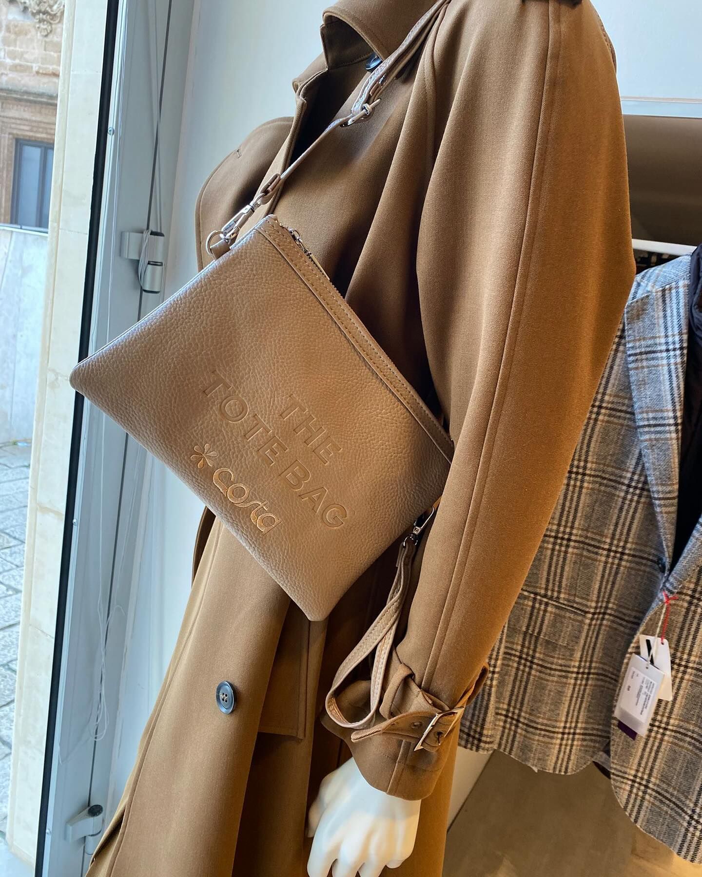 Manichino con trench color cuoio e borsa coordinata; espositore di un negozio di abbigliamento.