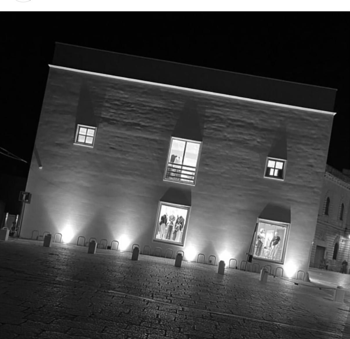 Coperta beige piegata e marsupio su uno scaffale contro una parete bianca.