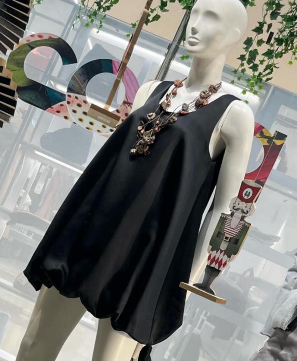 Manichino che indossa un piumino con paillettes, un top nero, pantaloni grigi e una cintura.