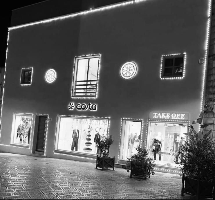 Interno di un negozio di abbigliamento con appendiabiti su pareti bianche e banchi da lavoro in legno.