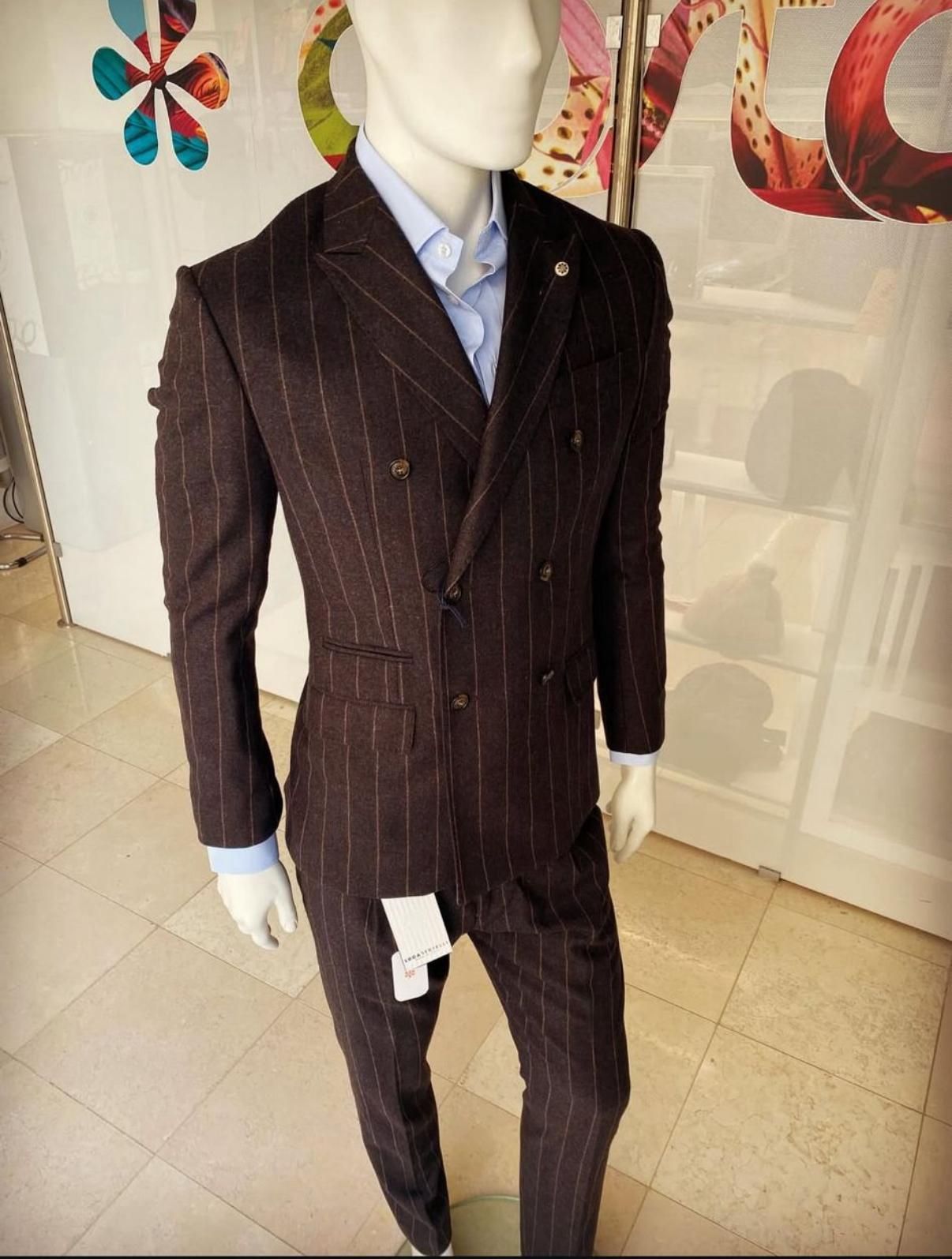 Manichino con giacca con cappuccio a spina di pesce sopra una maglietta scura, illuminato da luci soffuse.