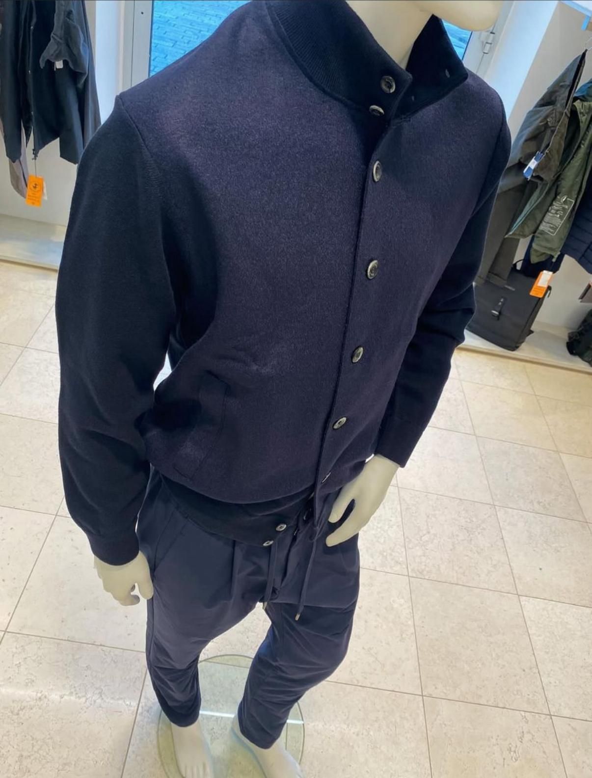 Manichino che indossa un piumino con paillettes, un top nero, pantaloni grigi e una cintura.