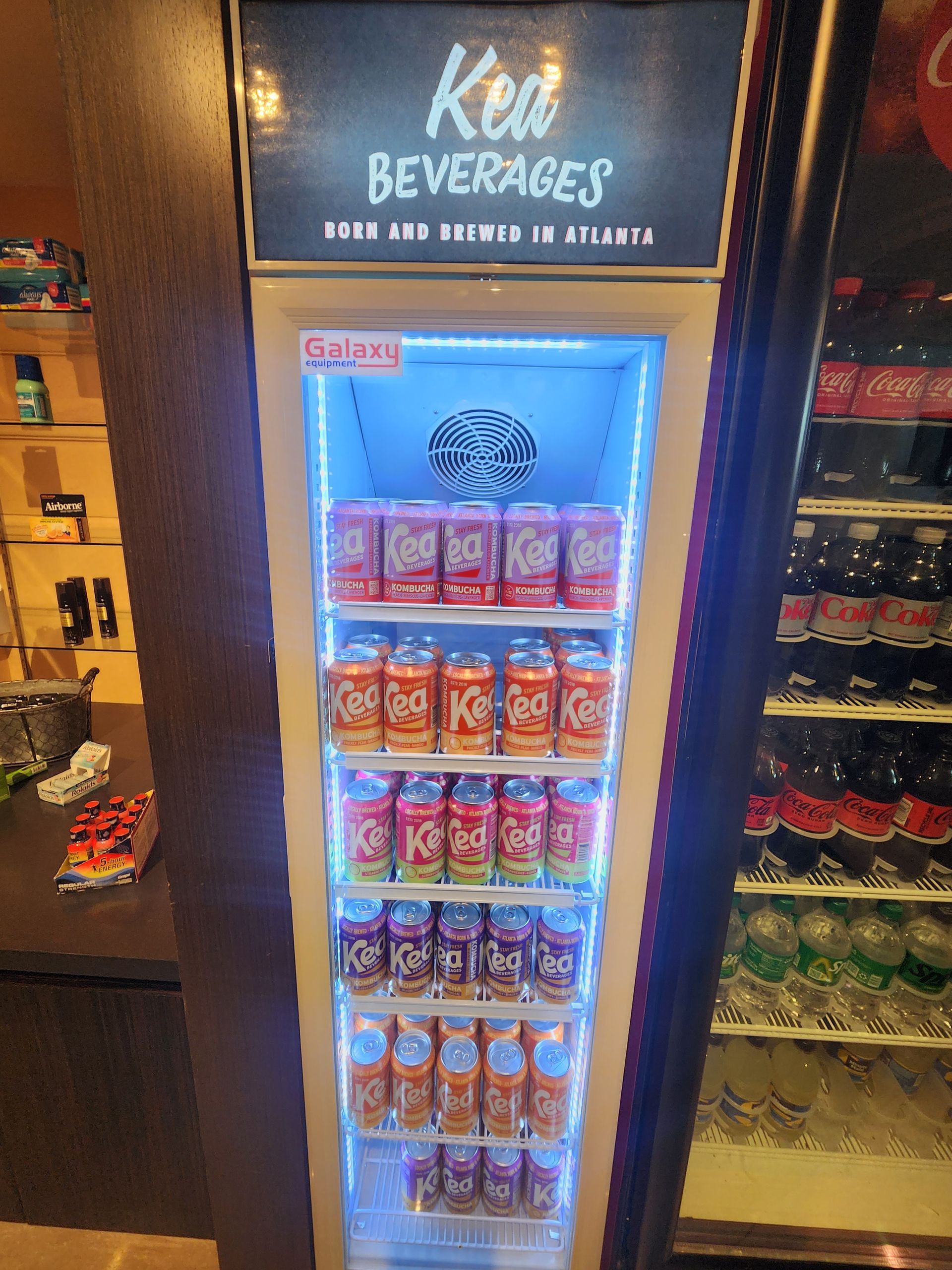 A refrigerator filled with various Coca-Cola products. The display is illuminated with blue light.