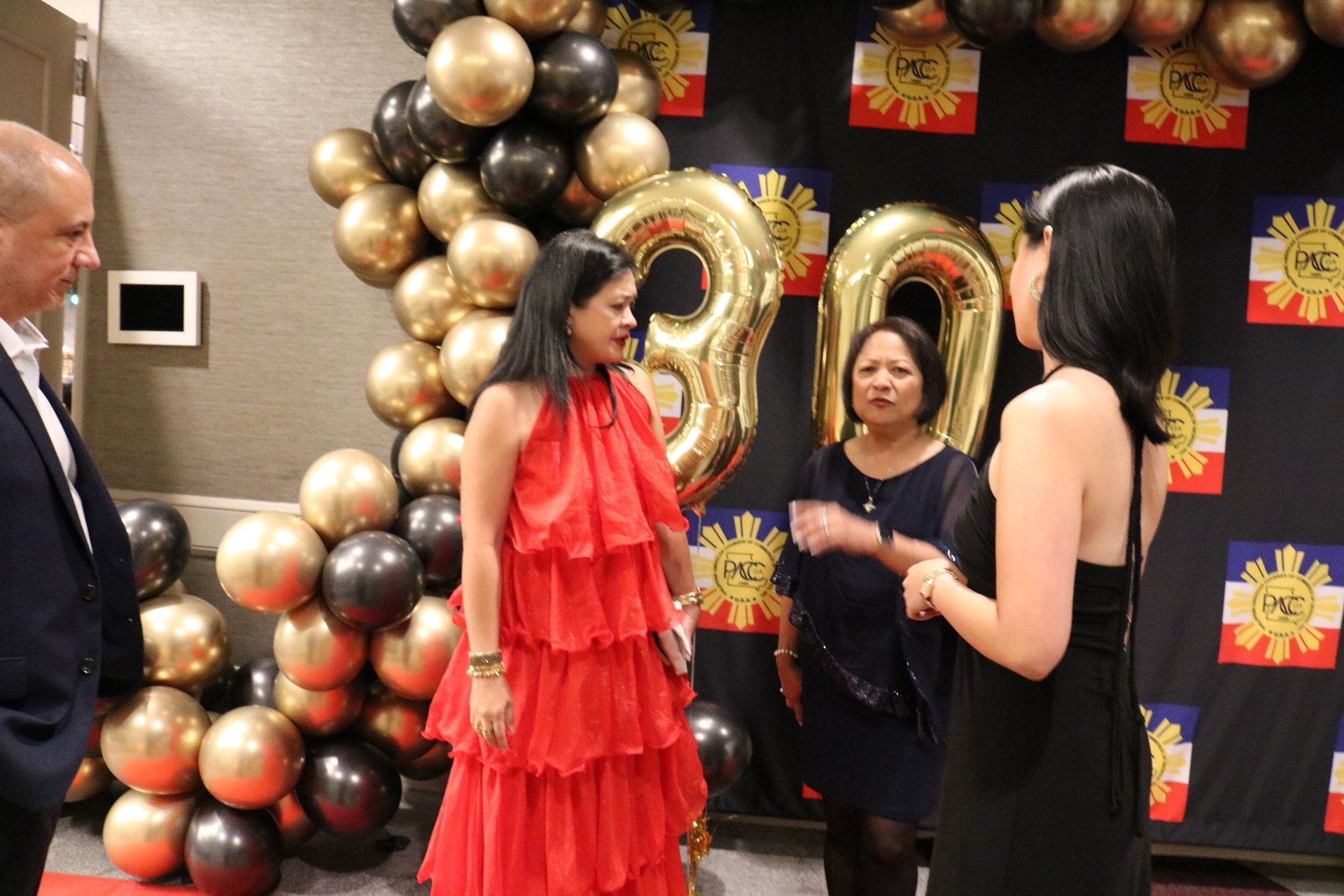 People at an event with gold and black balloons, a 