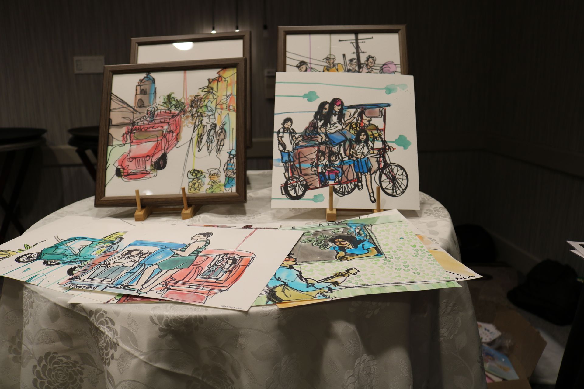 Artwork display: Sketches of people on bikes and in vehicles, various colors.