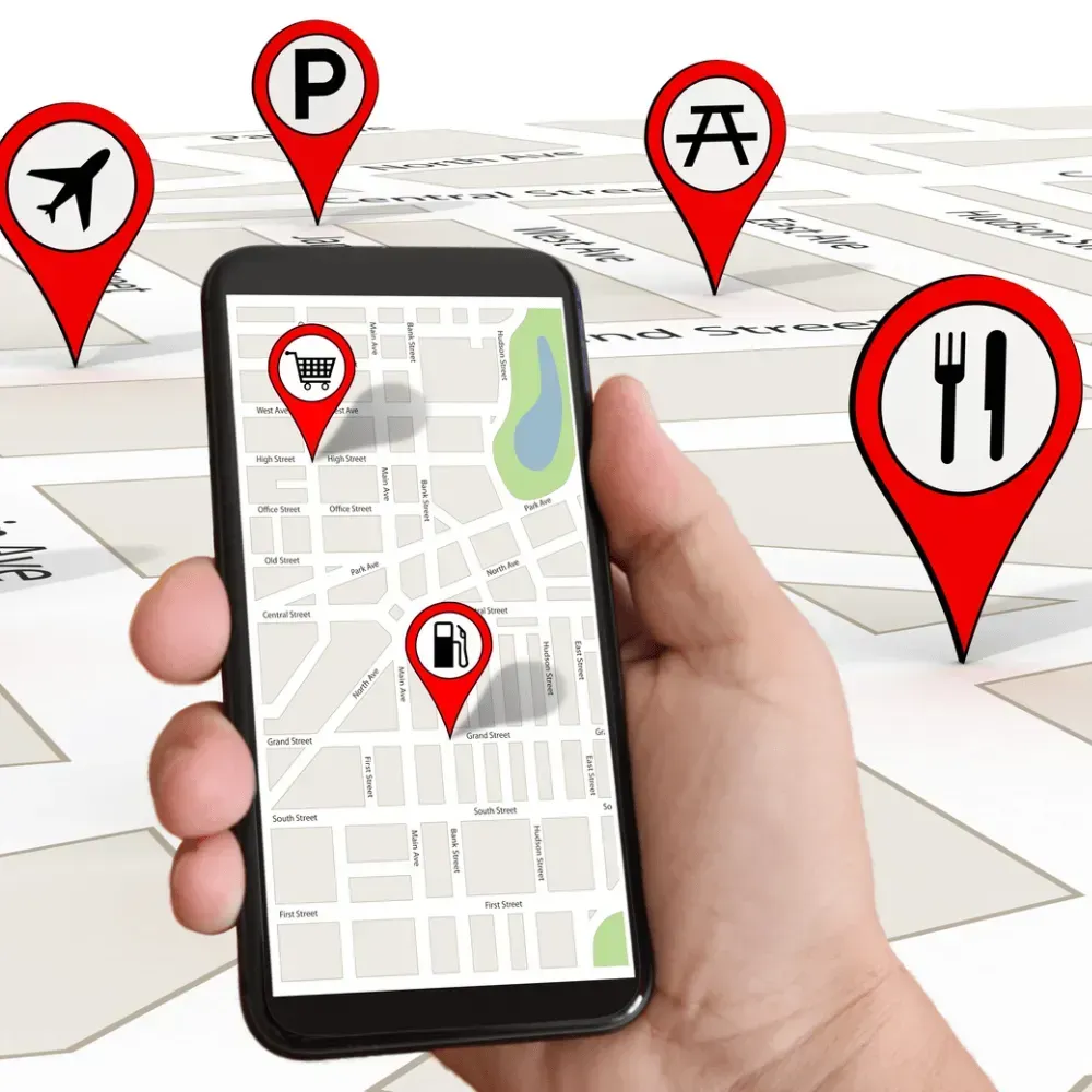 Hand holding phone displaying map with location markers for airplane, parking, picnic, shopping, gas station, and restaurant.