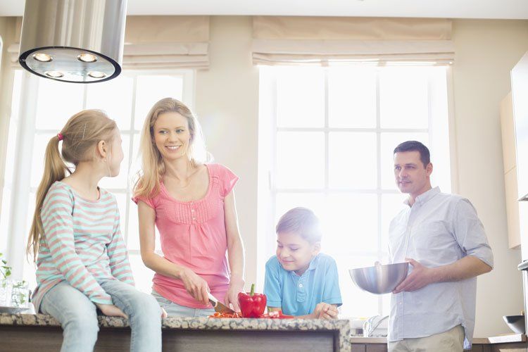 Family of four cooking together in kitchen