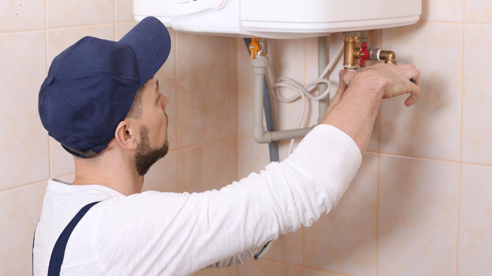 A plumber is fixing a water heater in an Independence bathroom.