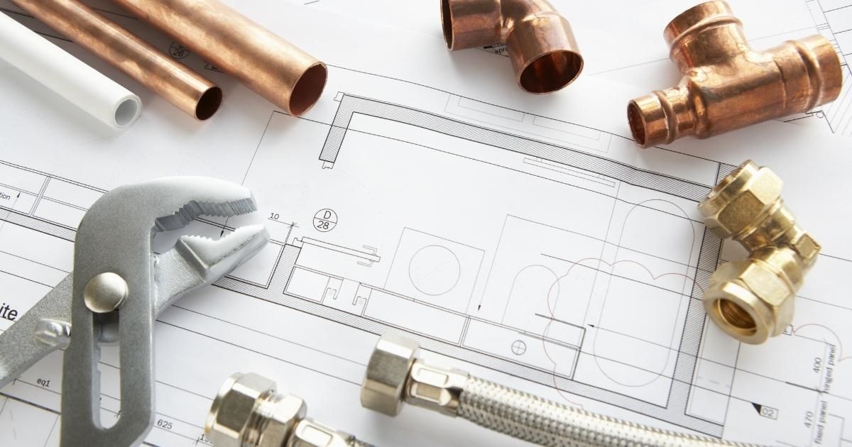 Plumbing tools and copper fittings on a technical blueprint drawing