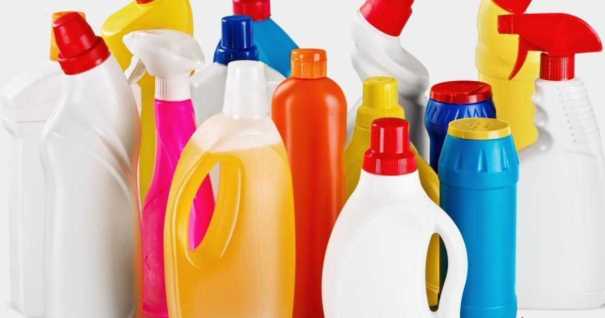 Assorted colorful plastic cleaning bottles and spray containers arranged in a row