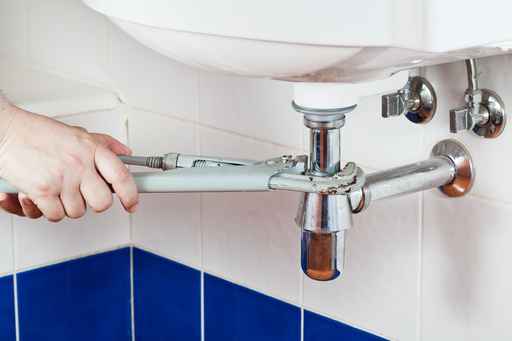 Person tightening sink's plumbing