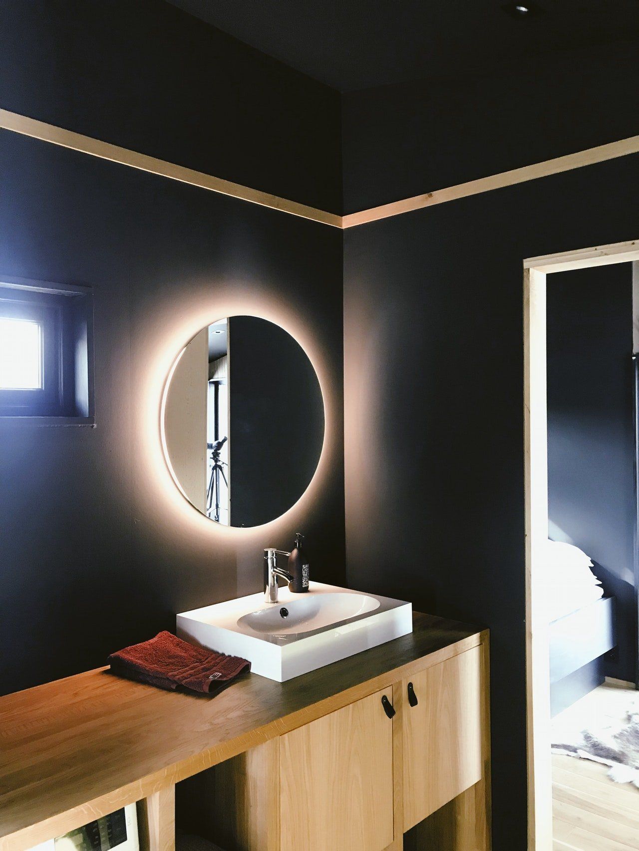 Spa-like bathroom with black walls and circle mirror