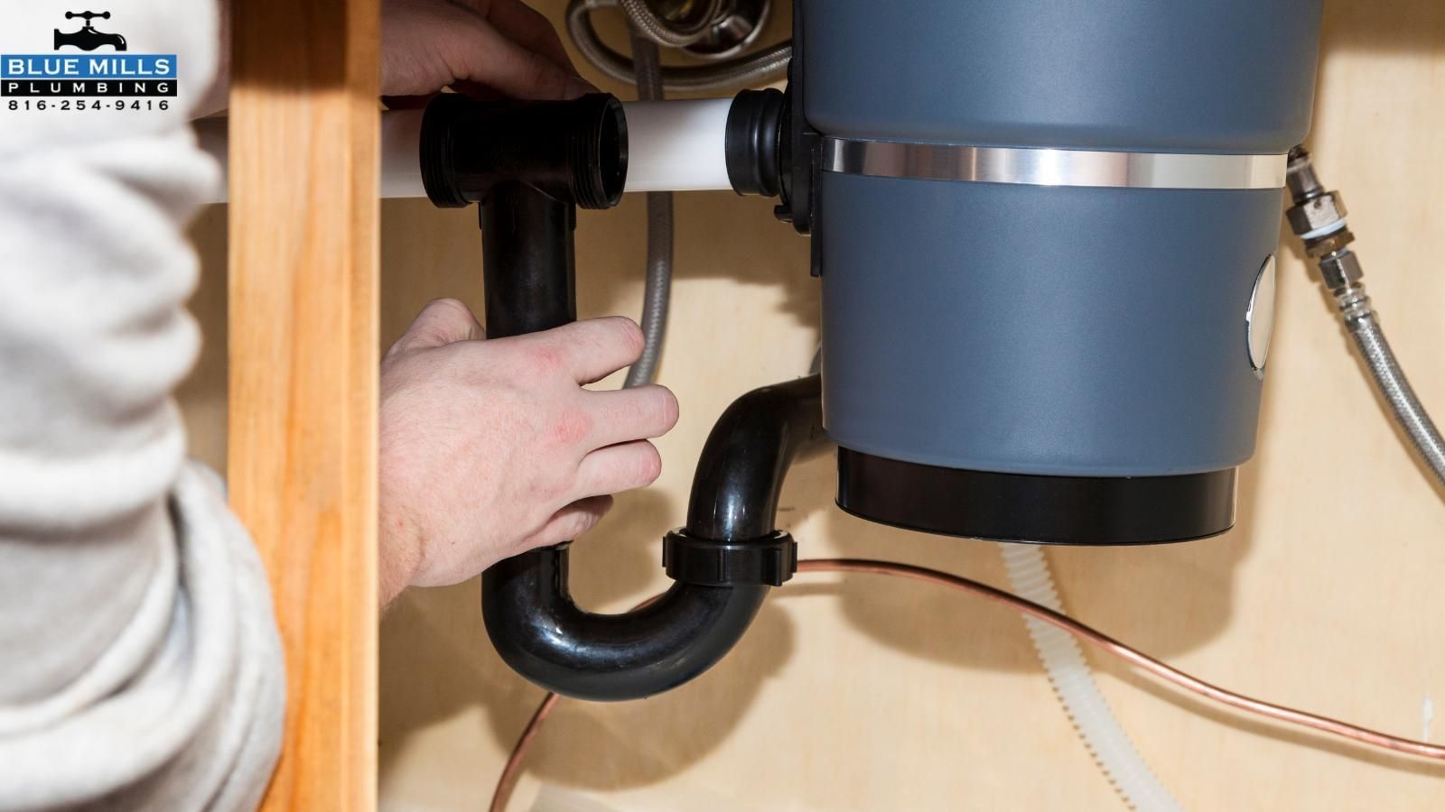 A person is fixing a garbage disposal under a sink.