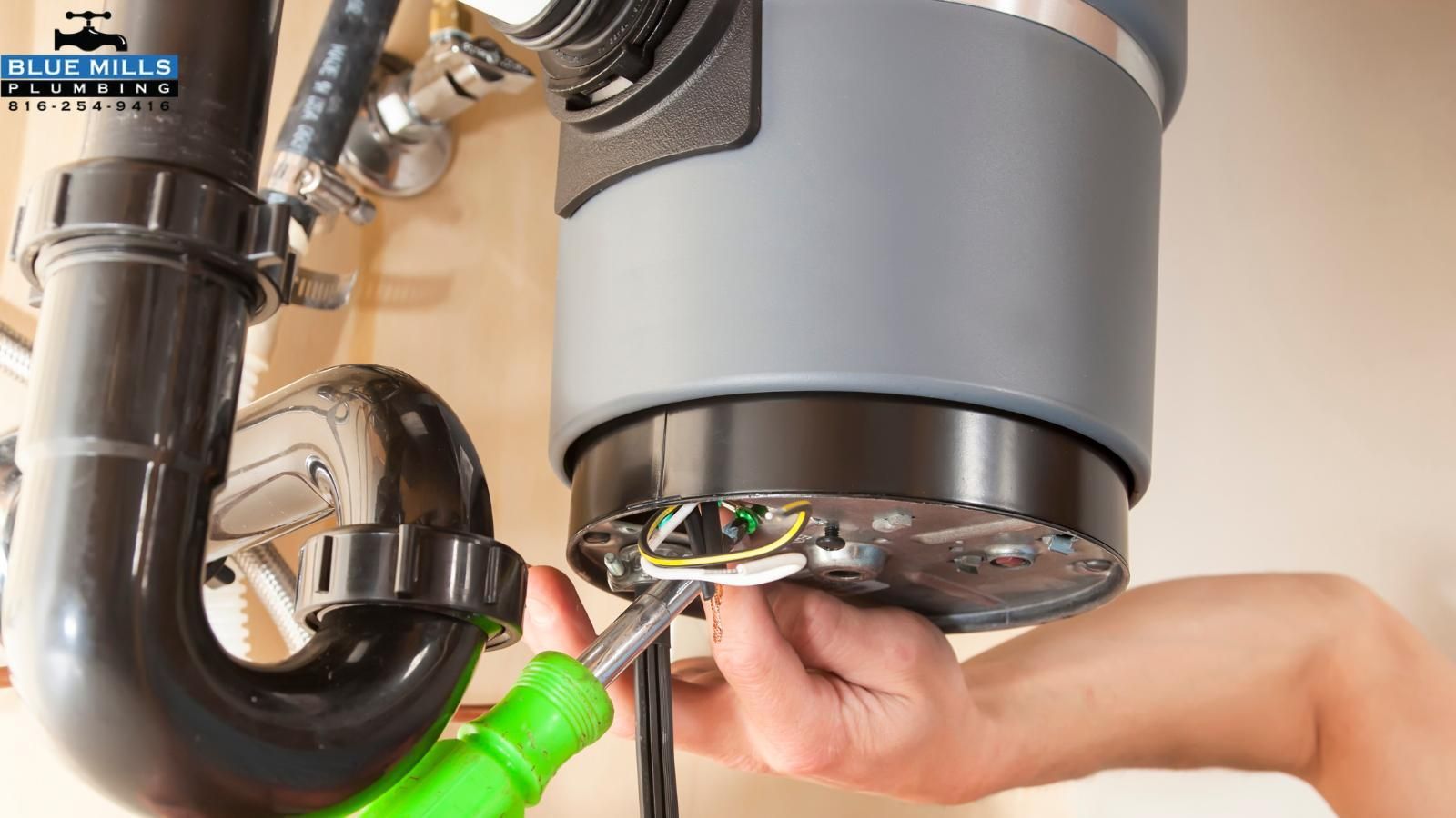 A person is fixing a garbage disposal under a sink.