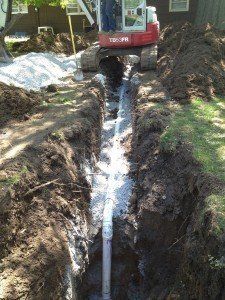 A red and white excavator is digging a hole in the ground.