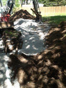 A bulldozer is digging a hole in the ground in a yard.