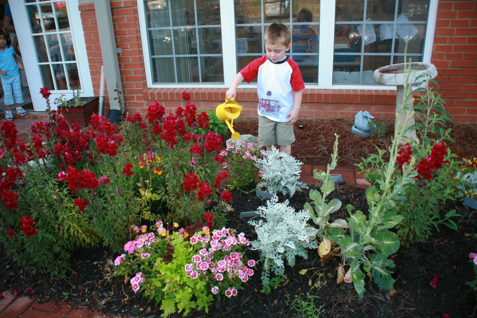 Montessori child watering flowers in the Toddler/Primary garden