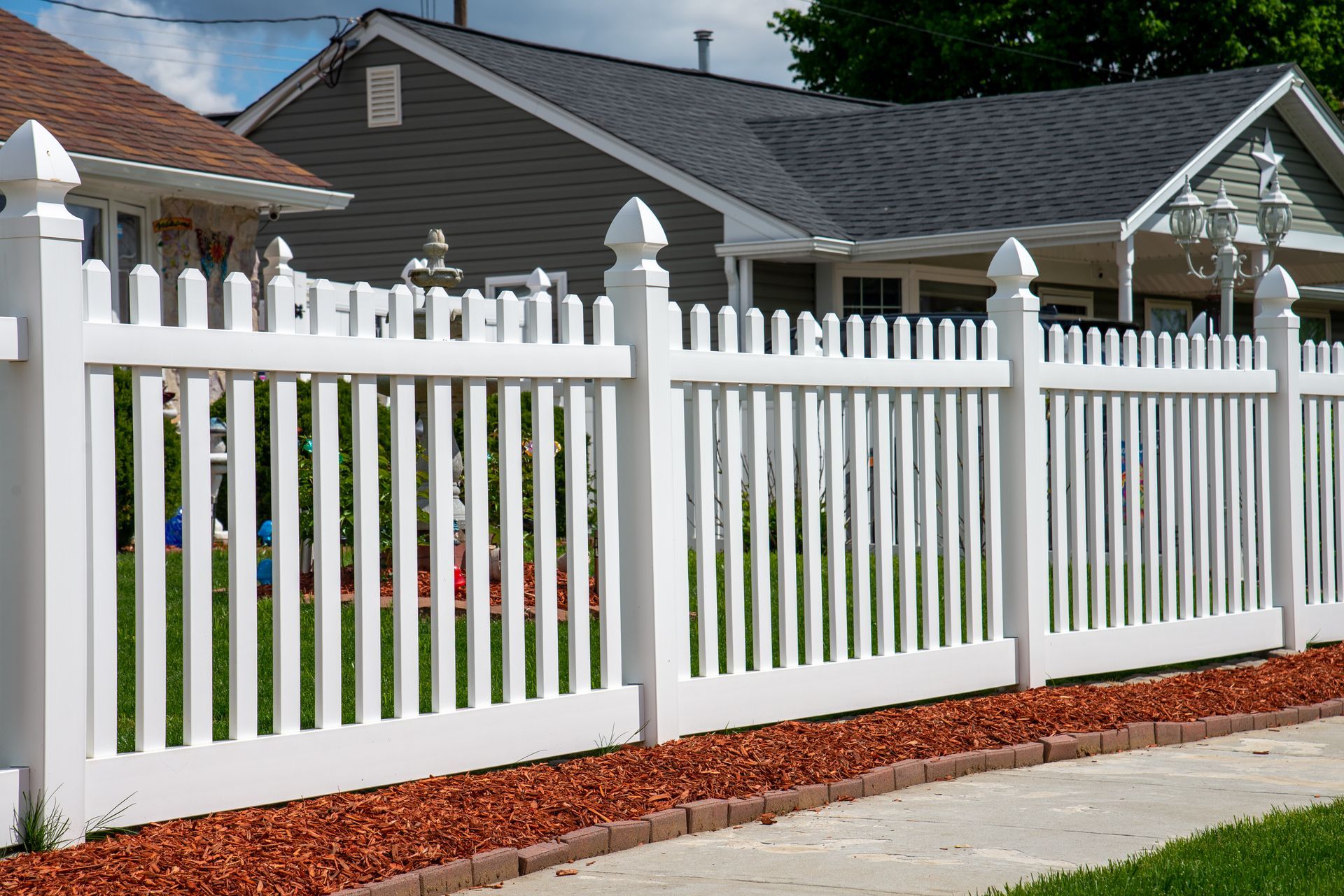 A white picket fence is in front of a house.