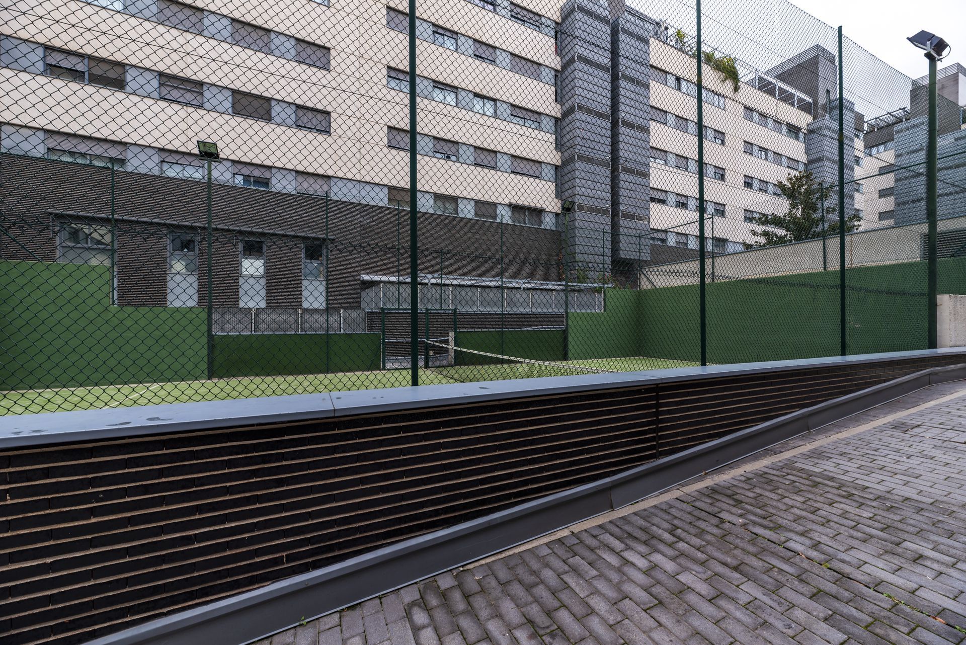 A fence surrounds a soccer field in front of a building.