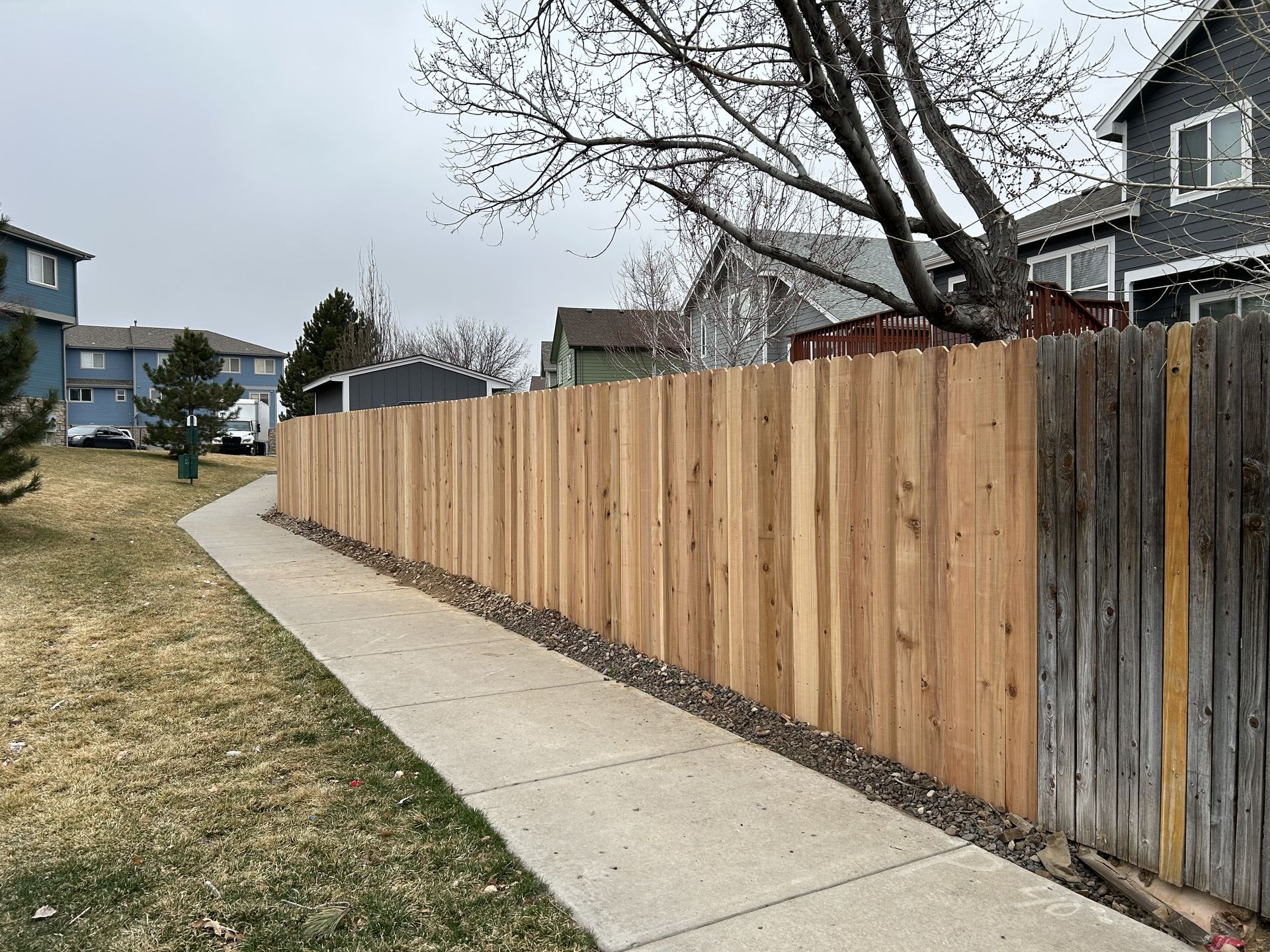 A wooden fence along a sidewalk next to a house.