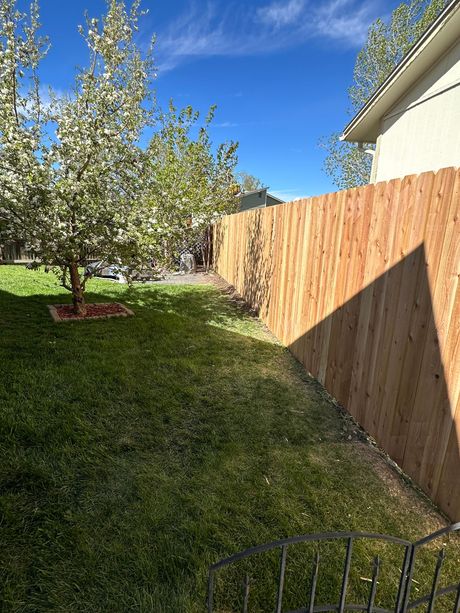 A wooden fence is in the backyard of a house.