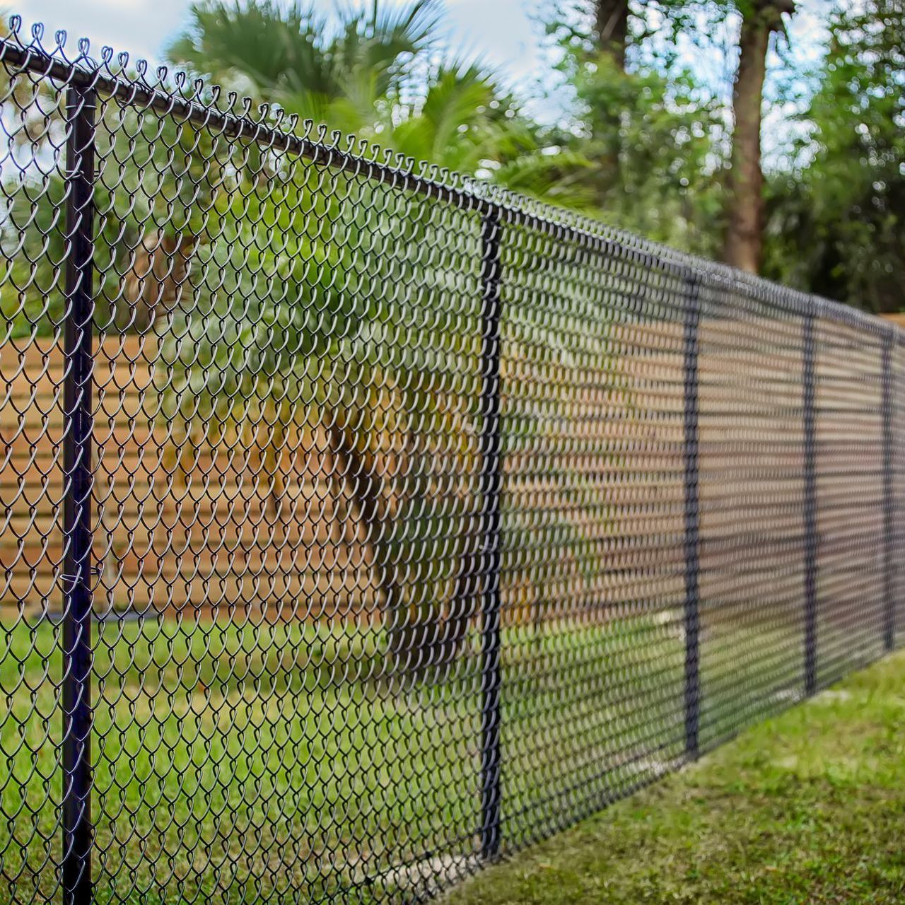 A chain link fence is surrounded by a wooden fence in a backyard.