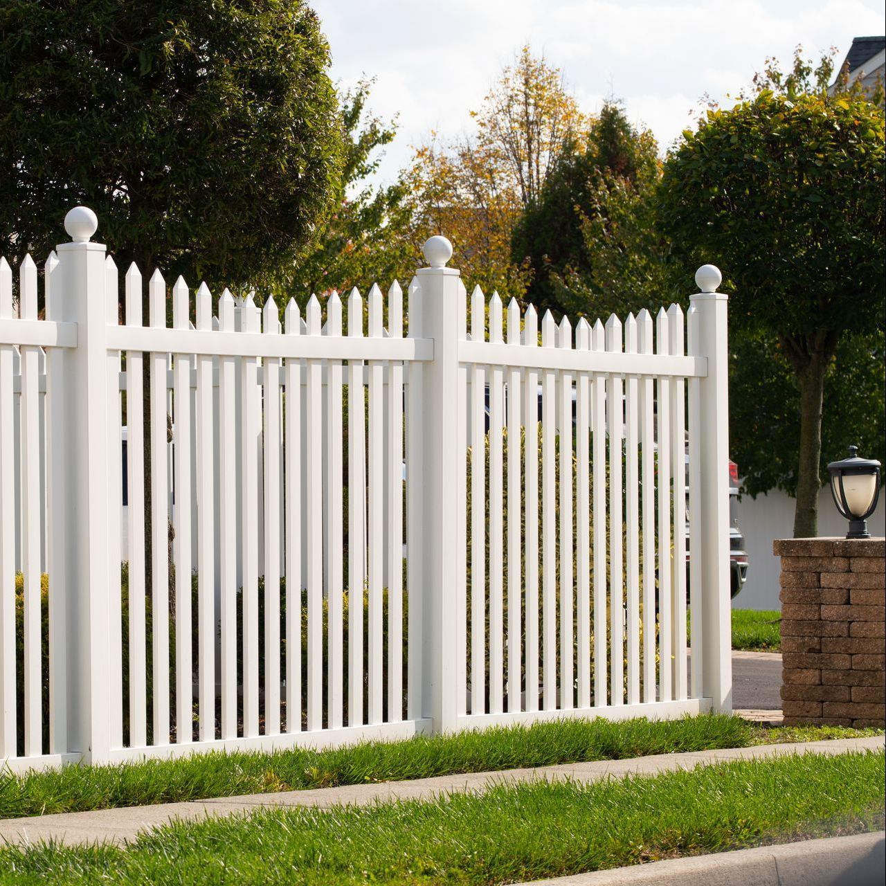 A white picket fence surrounds a lush green yard