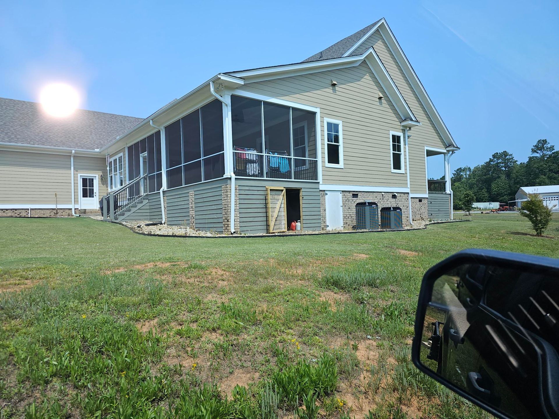 House with a screened porch and green lawn under a sunny sky.