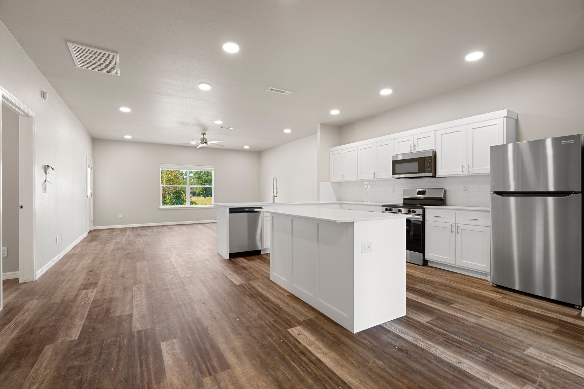A kitchen with white cabinets , stainless steel appliances , and hardwood floors.