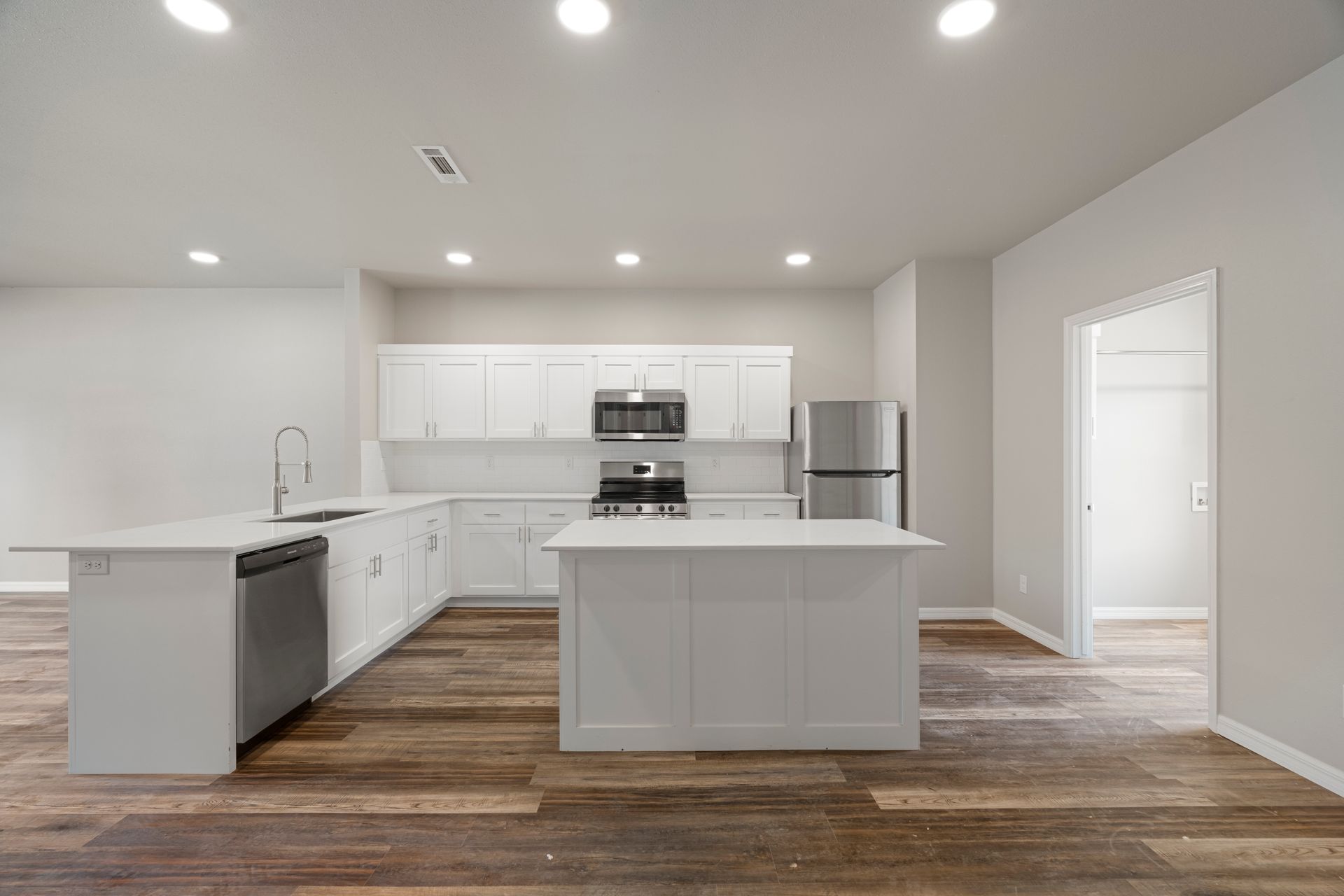 A kitchen with white cabinets , stainless steel appliances , and a large island.