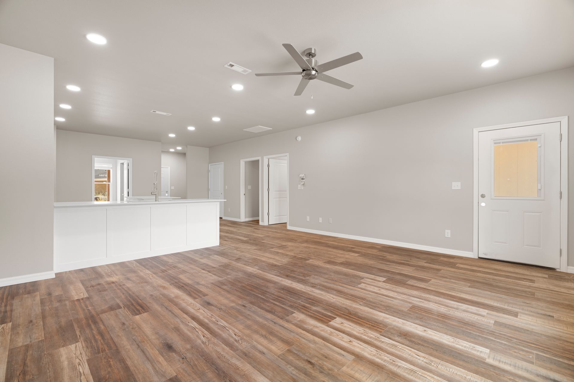 An empty living room with hardwood floors and a ceiling fan.