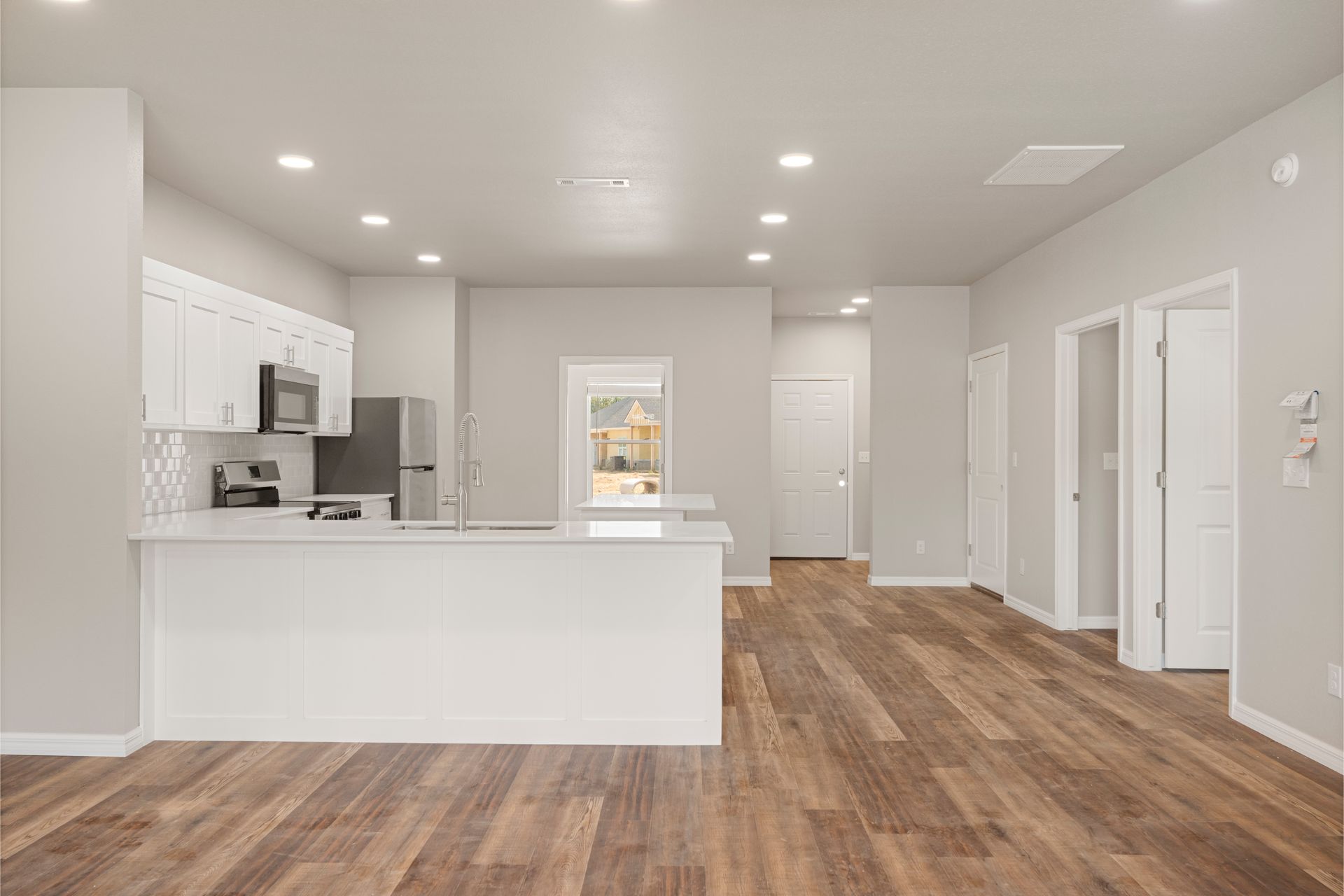 An artist 's impression of a kitchen with hardwood floors and white cabinets.