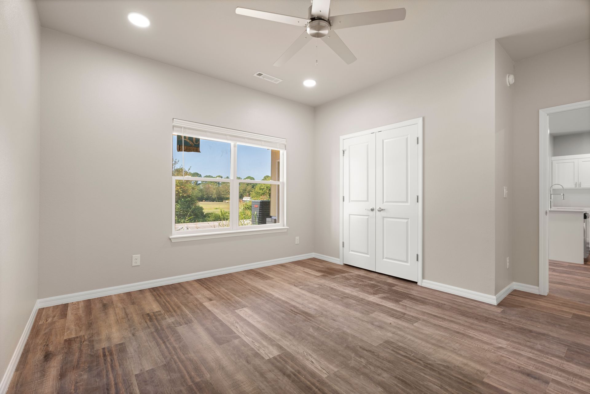 An empty room with hardwood floors and a ceiling fan.