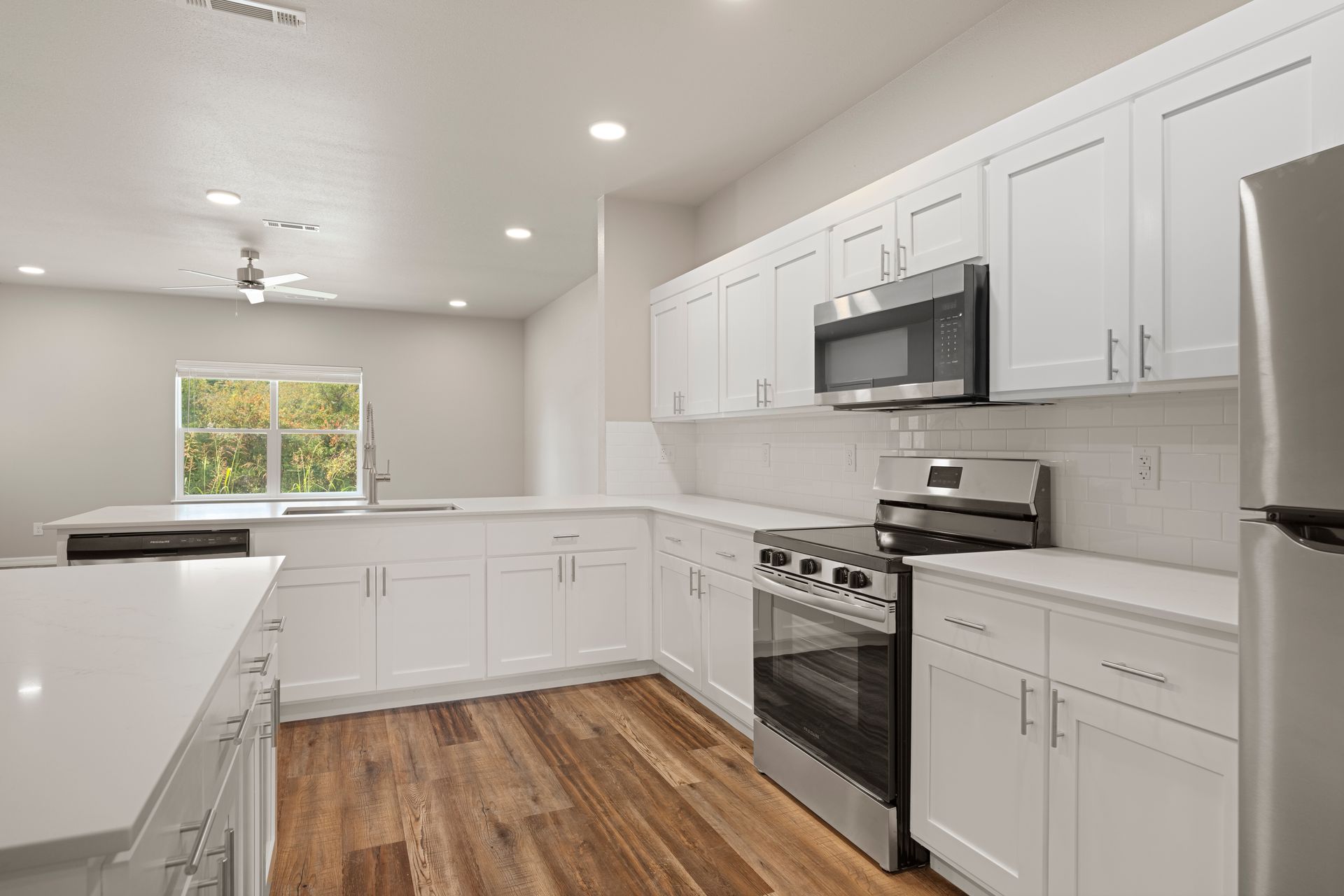 A kitchen with white cabinets , stainless steel appliances , and hardwood floors.