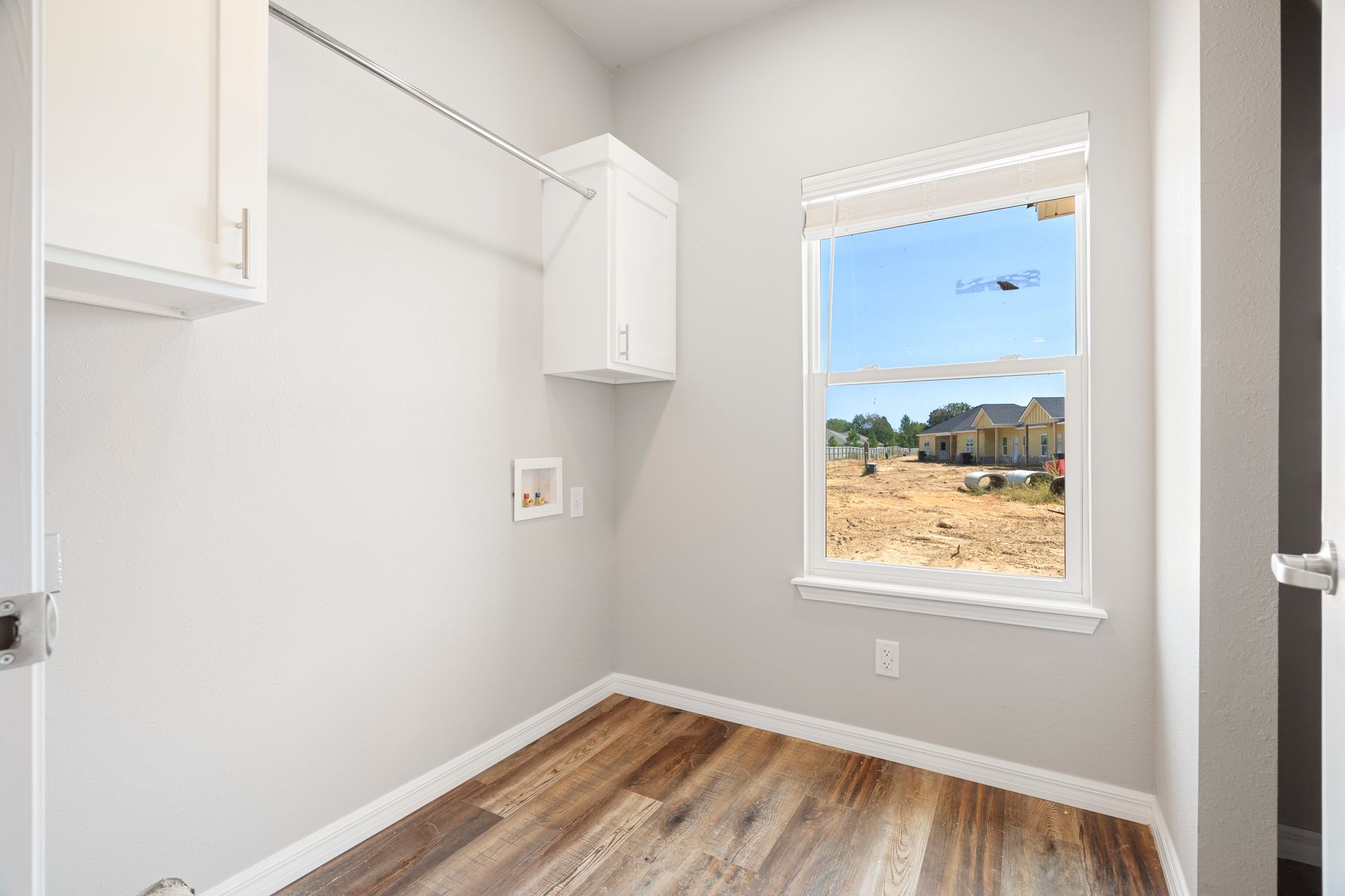 A laundry room with hardwood floors and a window.