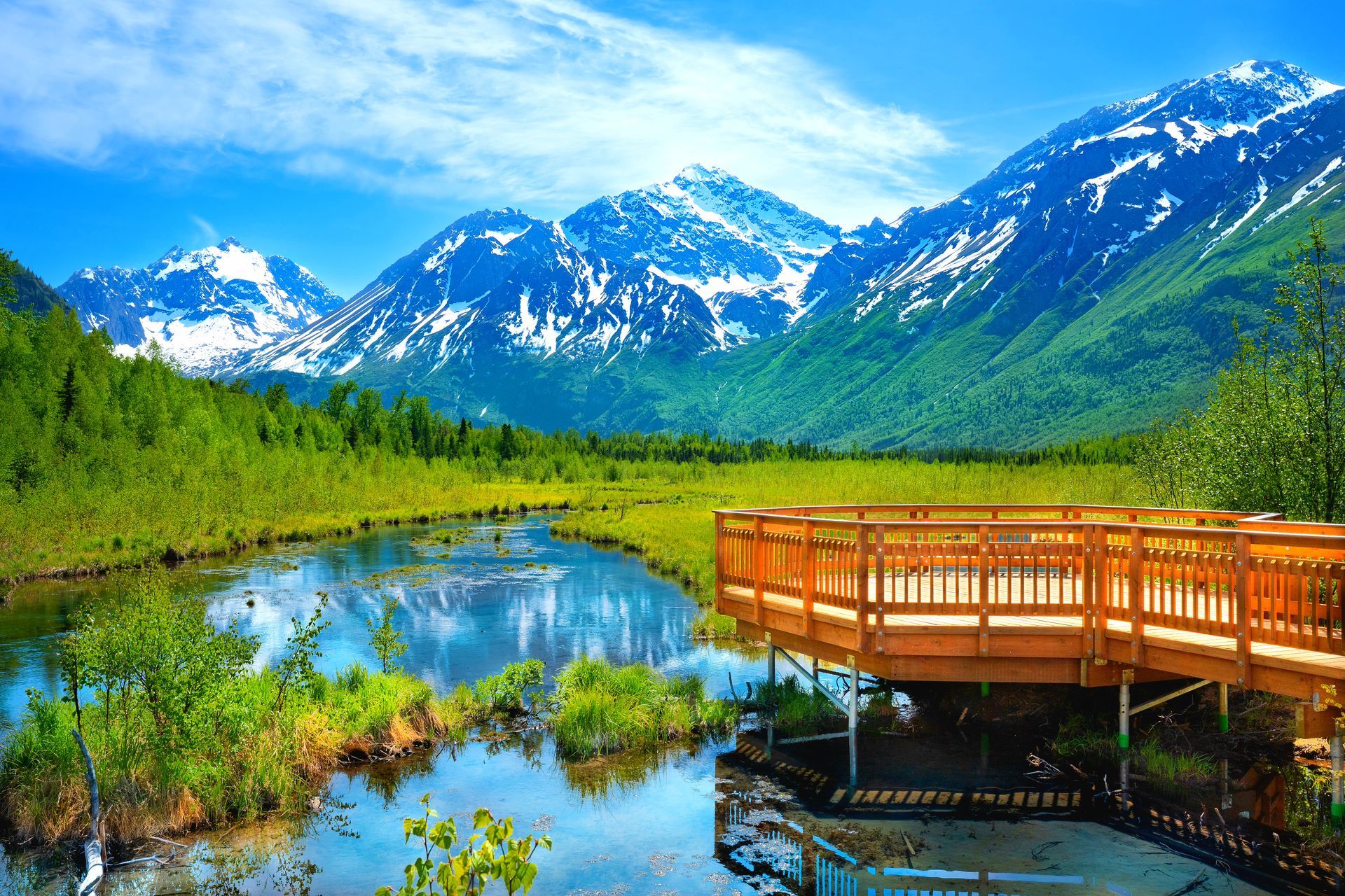A wooden bridge over a river with mountains in the background