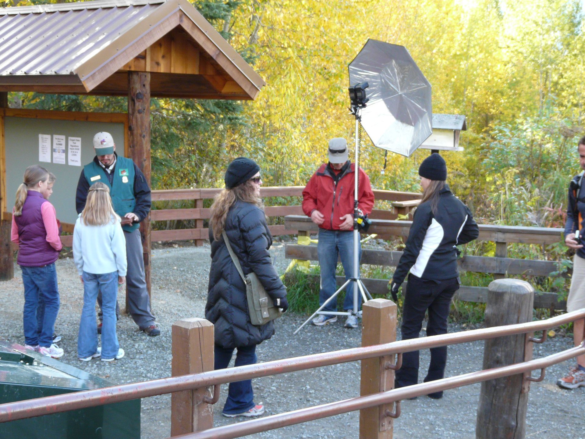 A group of people are standing around a wooden fence