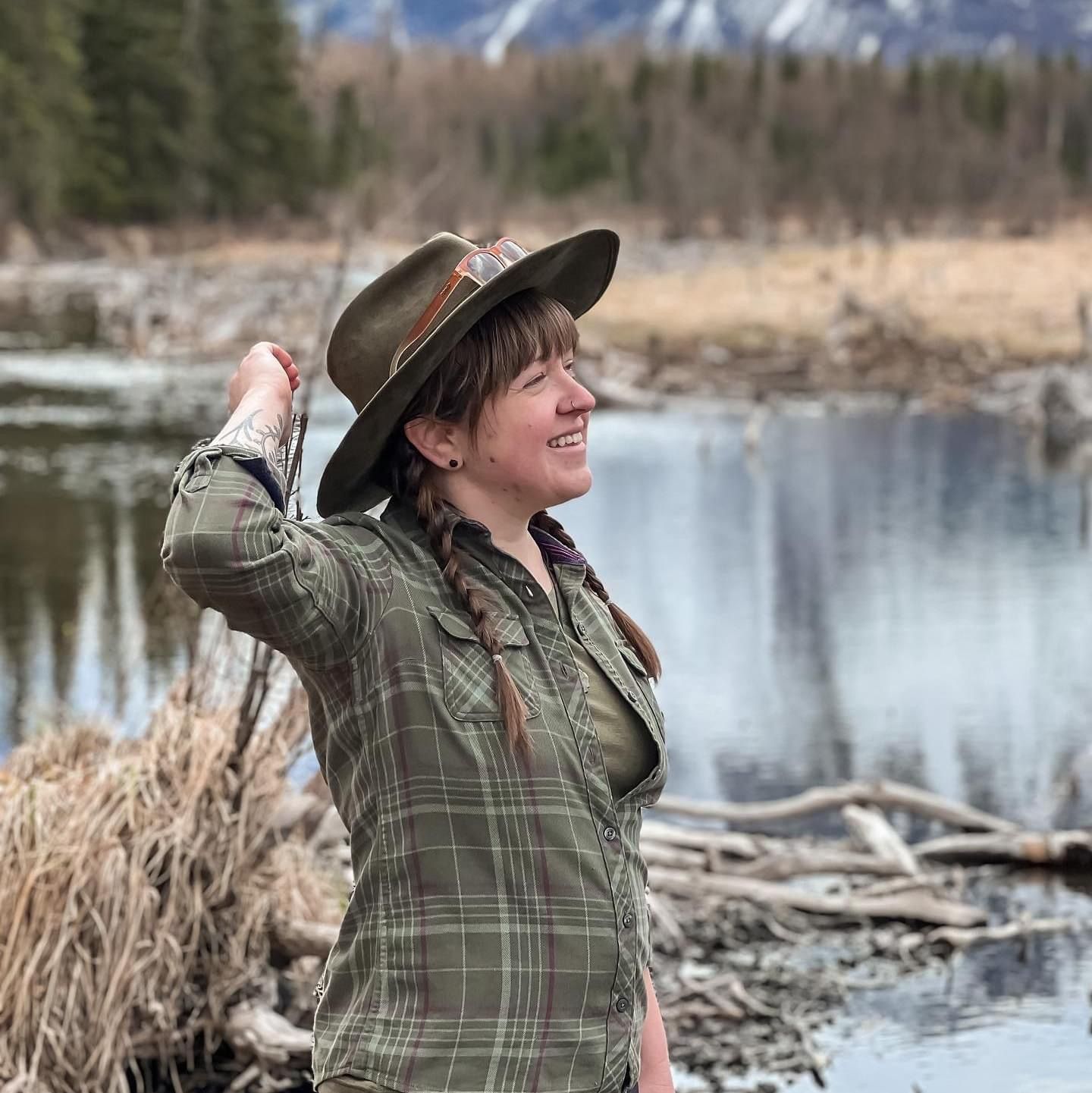 A woman wearing a hat is standing next to a body of water.