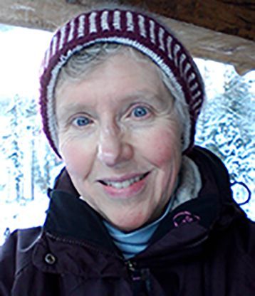 A woman wearing a hat and a jacket is smiling for the camera.