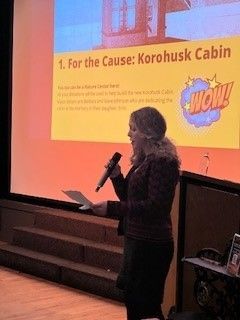A woman is holding a microphone in front of a screen that says wow.