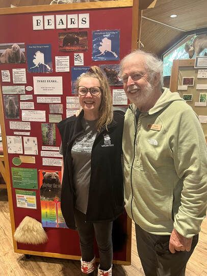 A man and a woman are posing for a picture in front of a sign that says bears
