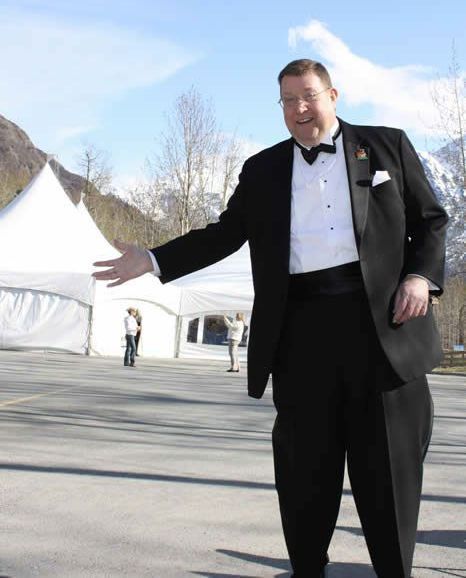 A man in a tuxedo is standing in front of a white tent