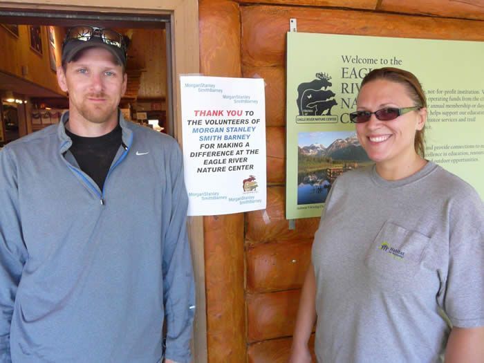 A man and a woman standing in front of a sign that says thank you