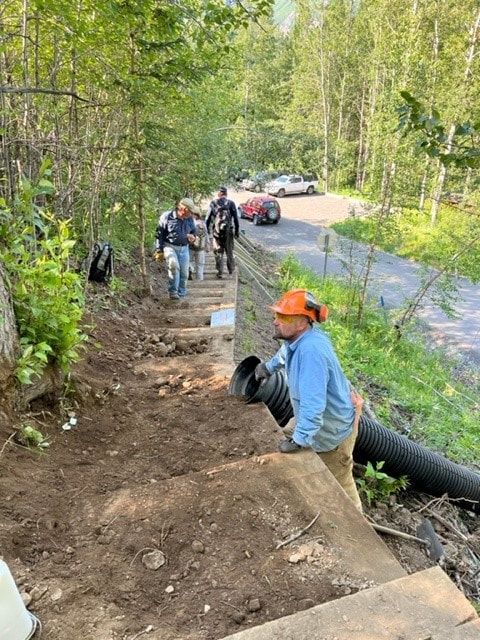 A group of people are working on a set of stairs in the woods.